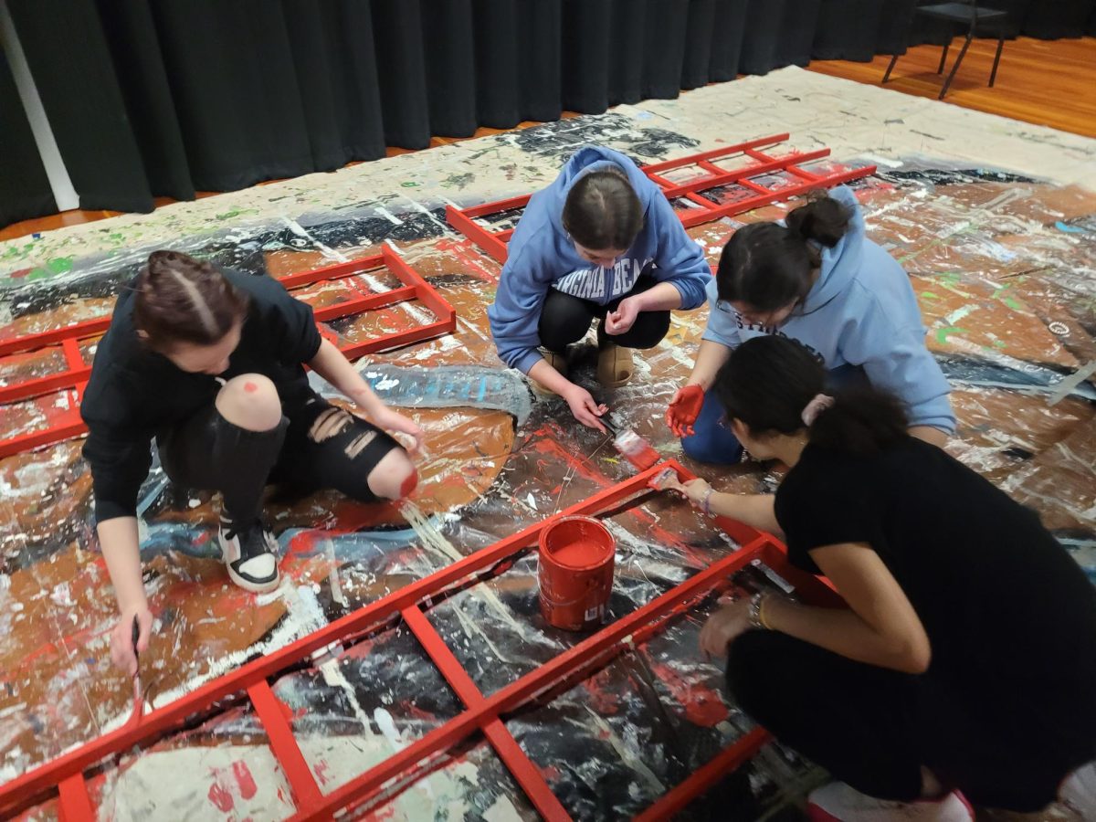 Four backstage theater students work on painting a set piece ahead of Fitch’s musical, A Smooth Takeover.

